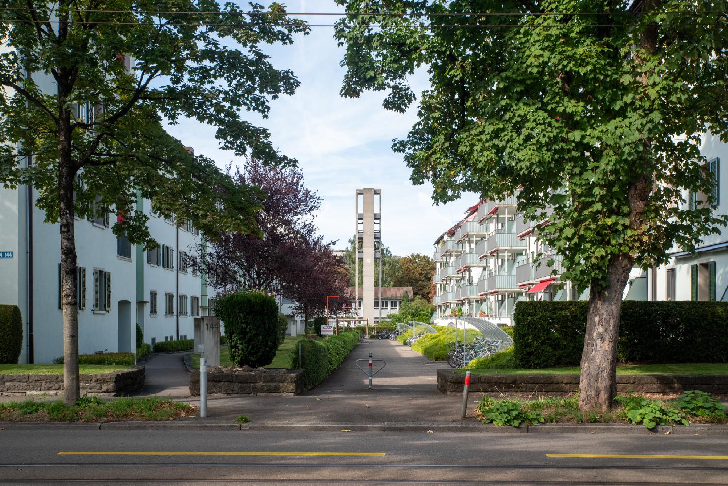 A perpendicular service road on Albisriederstrasse that serves 4 buildings on each side of the street. The campanile of Andreaskirche is visible at the end of the street.