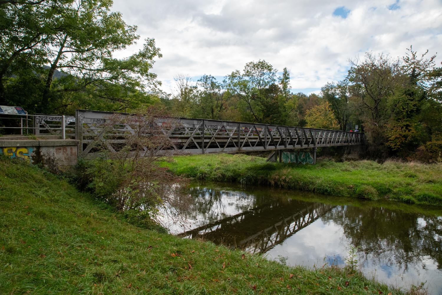 Allmendbrücke in Zürich: a bridge with metallic rails above a river, that reflects both the bridge and its surroundings